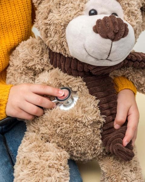 cropped shot of girl with stethoscope listening to teddy bear br urgent care with compassion
